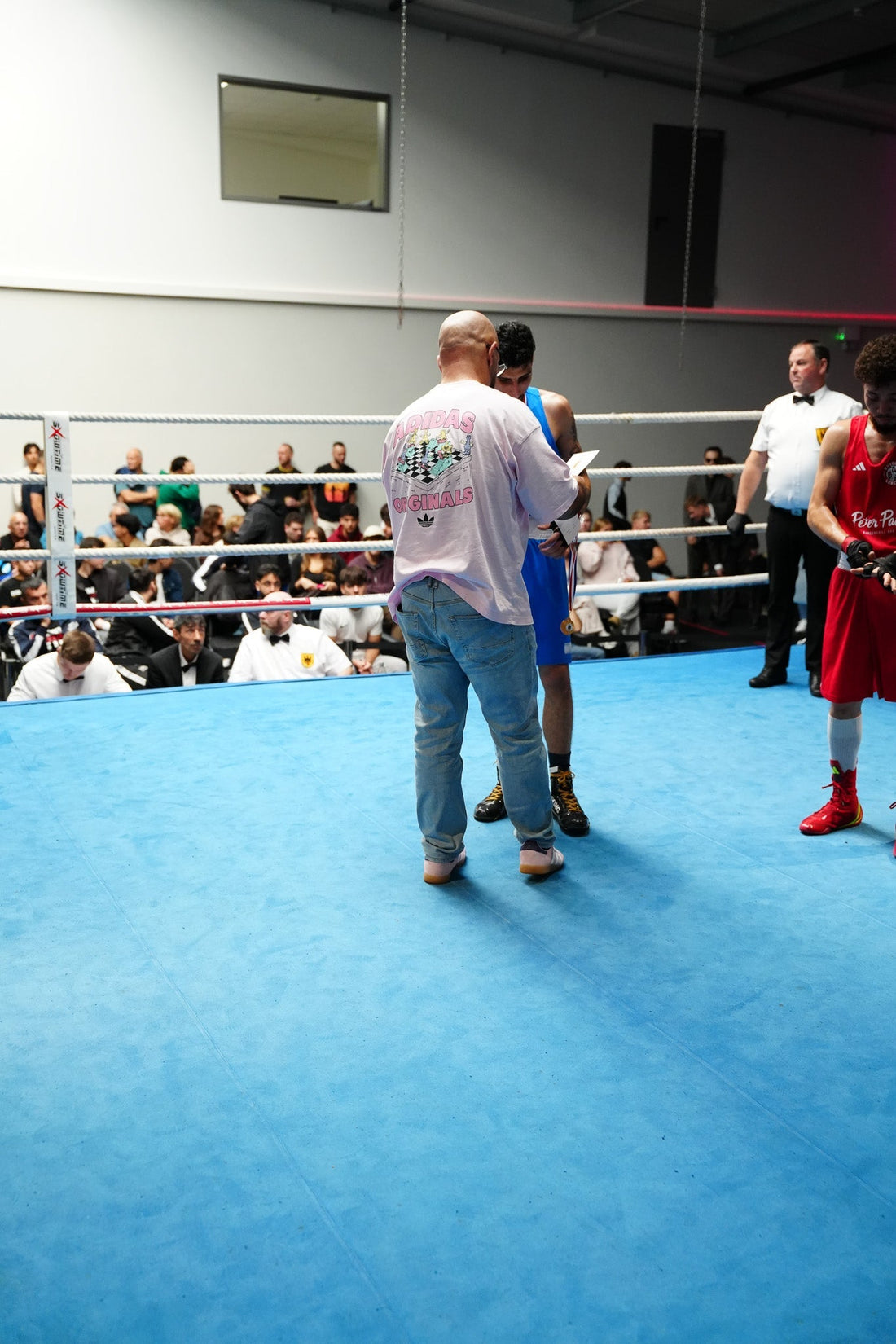 Boxring mit Ringrichter, Boxern und Offiziellen am Ring bei einer Boxveranstaltung