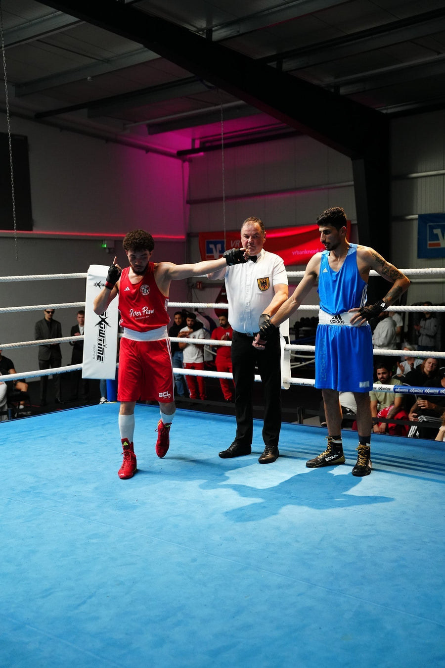 Ringrichter mit Boxern zur Urteilsverkündung nach einem Boxkampf – Rund um Ring & Halle