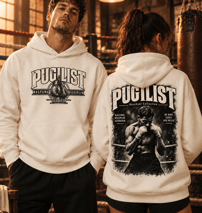 Mann und Frau tragen Natural Raw PUGILIST Ultra Heavy Hoodies mit Front- und Rückenprint in einer alten Boxhalle